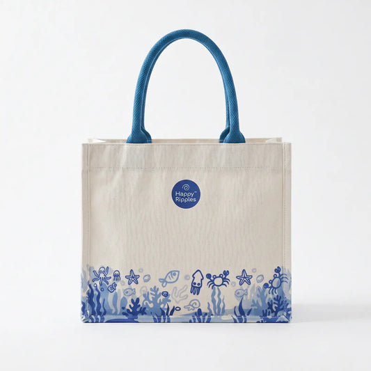 Happy Ripples ocean-print canvas tote bag with blue handles on white background.
