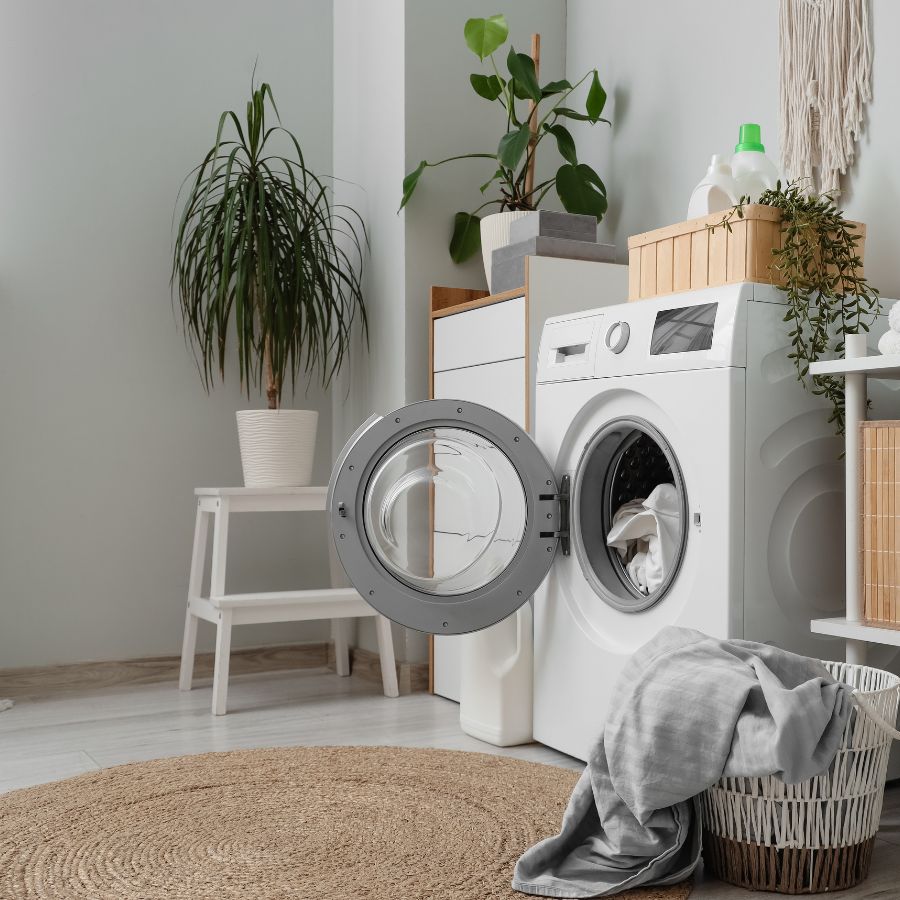Bright laundry room with front load washing machine plants and laundry basket for Happy Ripples laundry care lifestyle