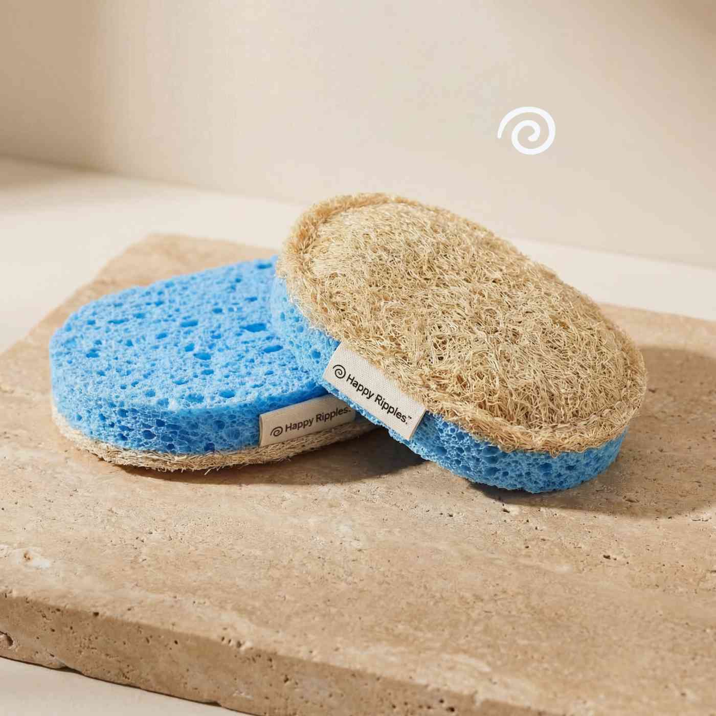 Happy Ripples loofah sponge with blue scrub layer on stone surface.
