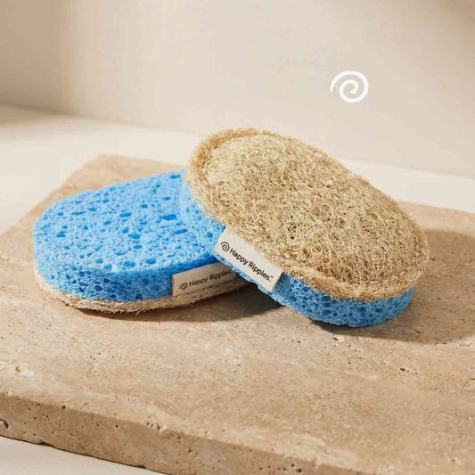Happy Ripples loofah sponge with blue scrub layer on stone surface.
