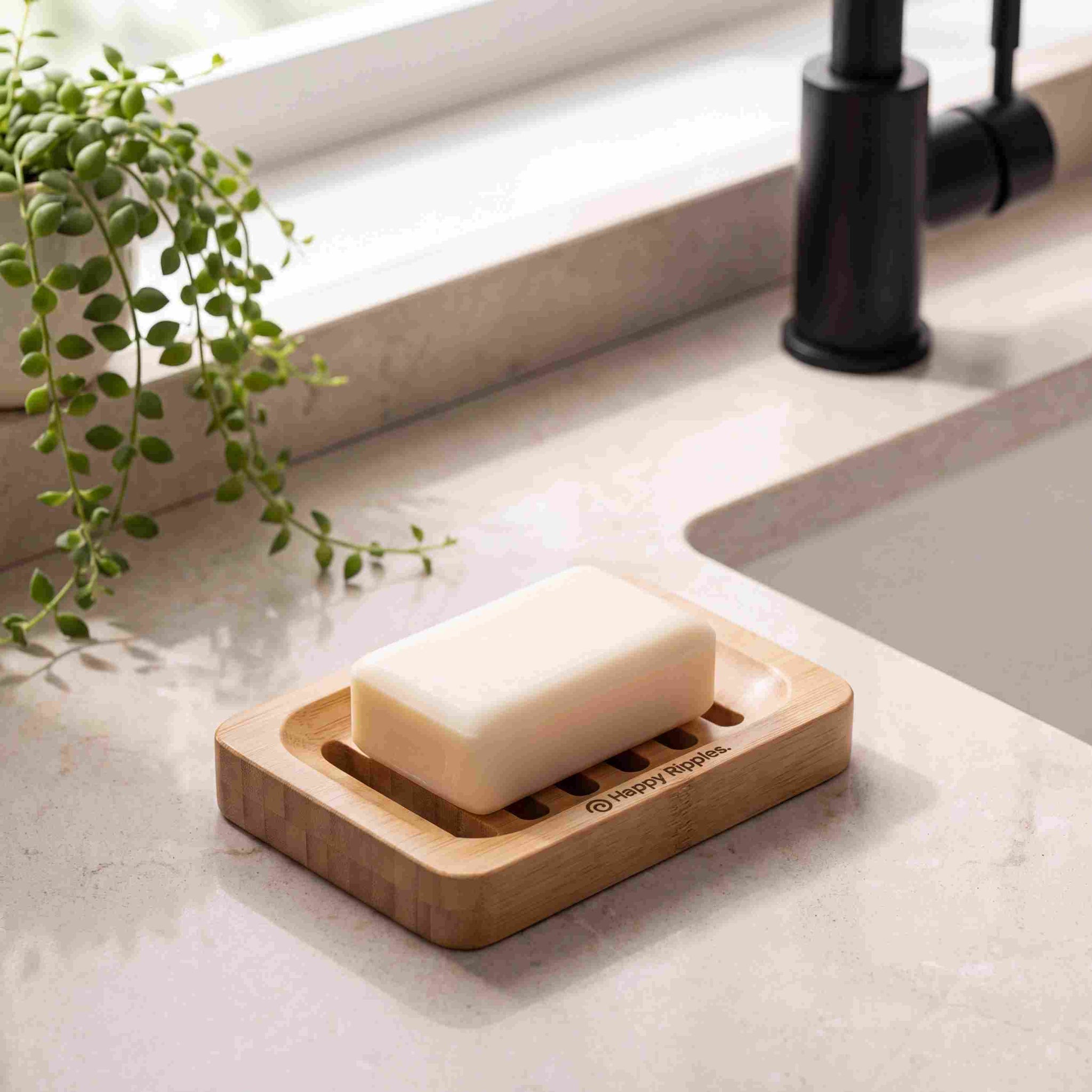 Happy Ripples soap bar resting on a wooden soap dish beside a bathroom sink.